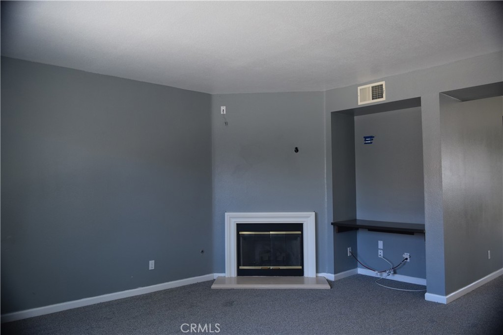 Unfurnished living room with a white-trimmed fireplace and recessed media alcove.