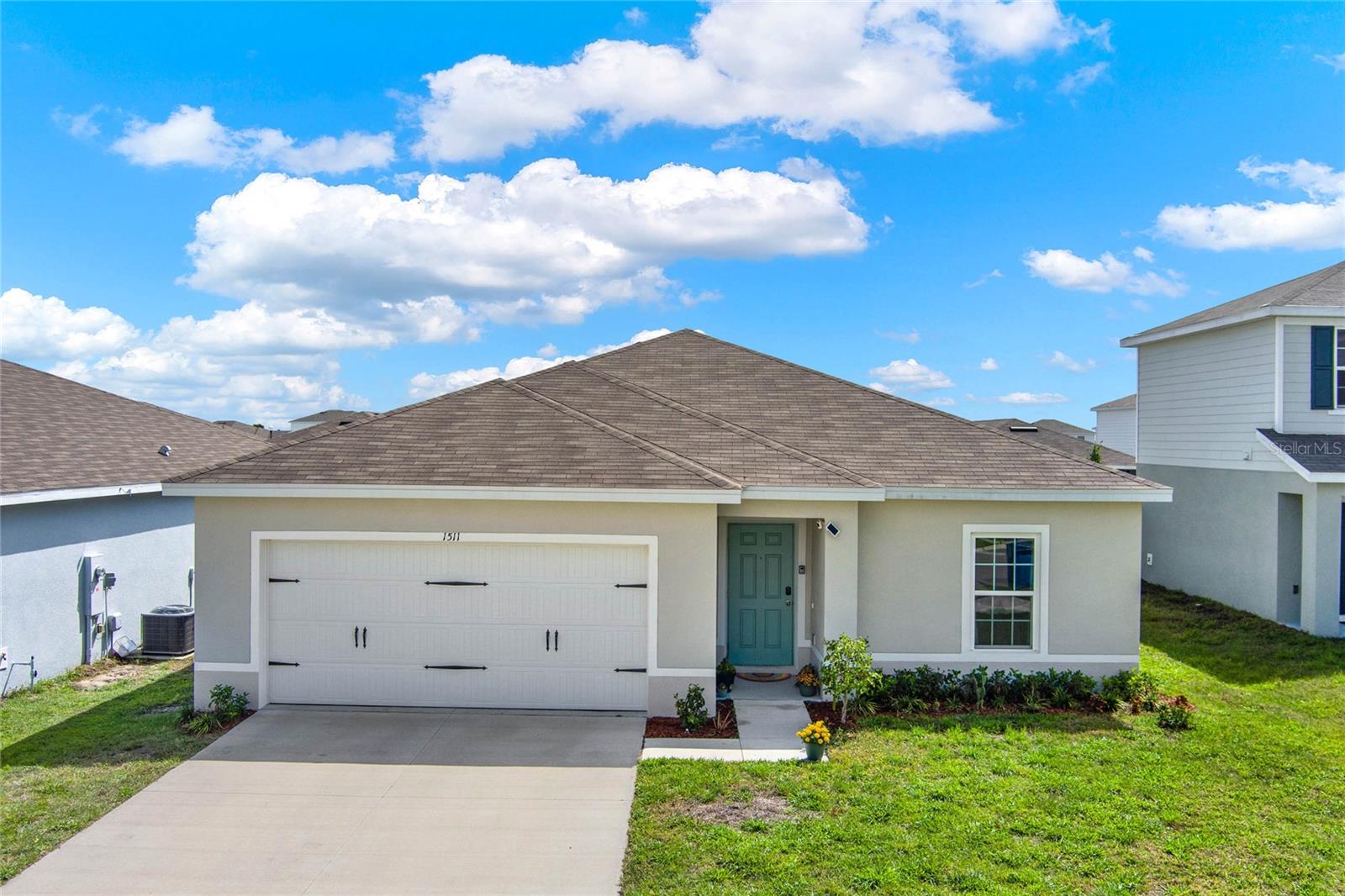 Single-story home with a brown hip roof, white double garage, and teal front door.