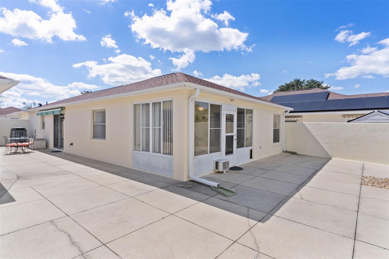 Single-story home with a screened porch and expansive concrete patio.