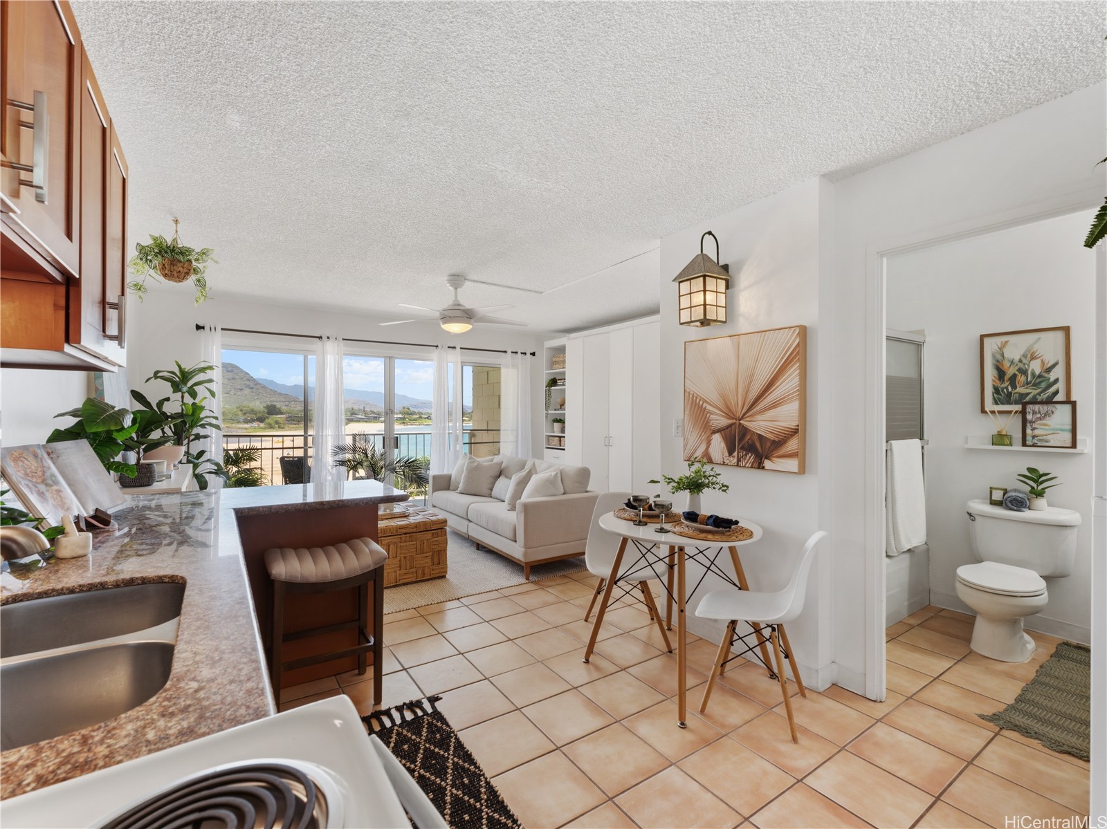 Open-plan kitchen and living area with ocean and mountain views through sliding glass doors.