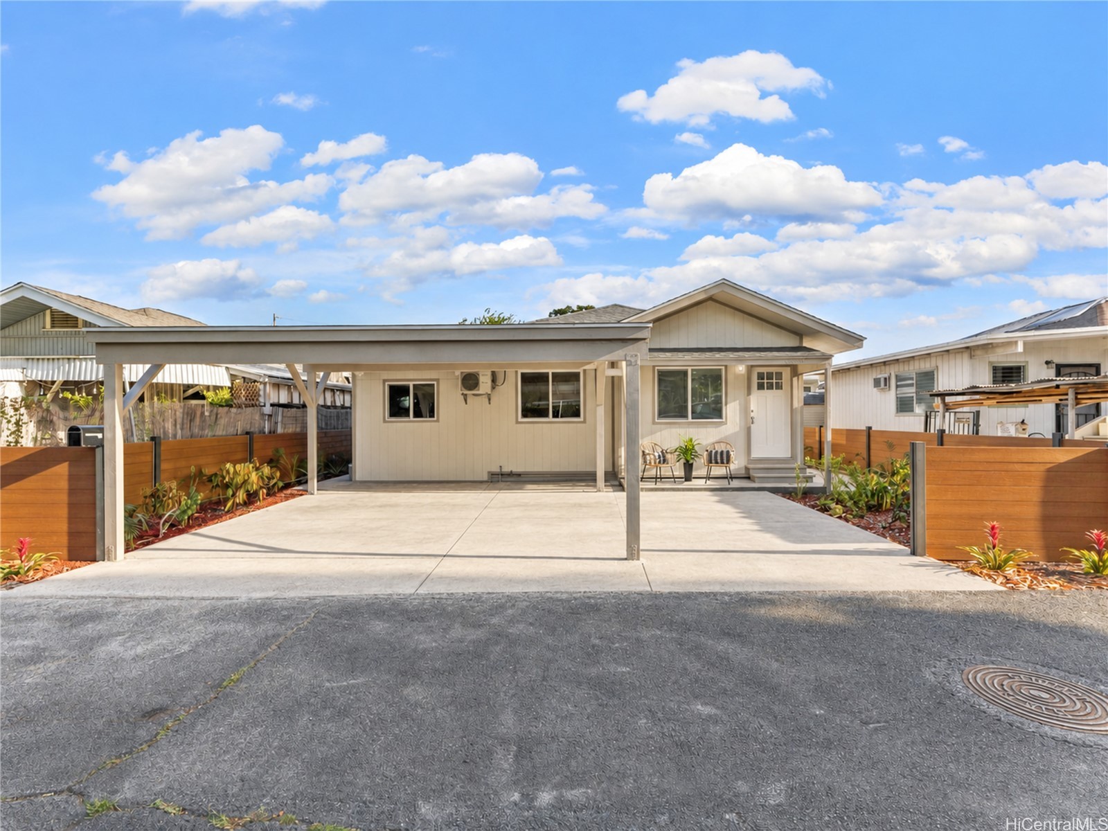 Single-story home with a wide covered carport, paved driveway, and wooden privacy fences.