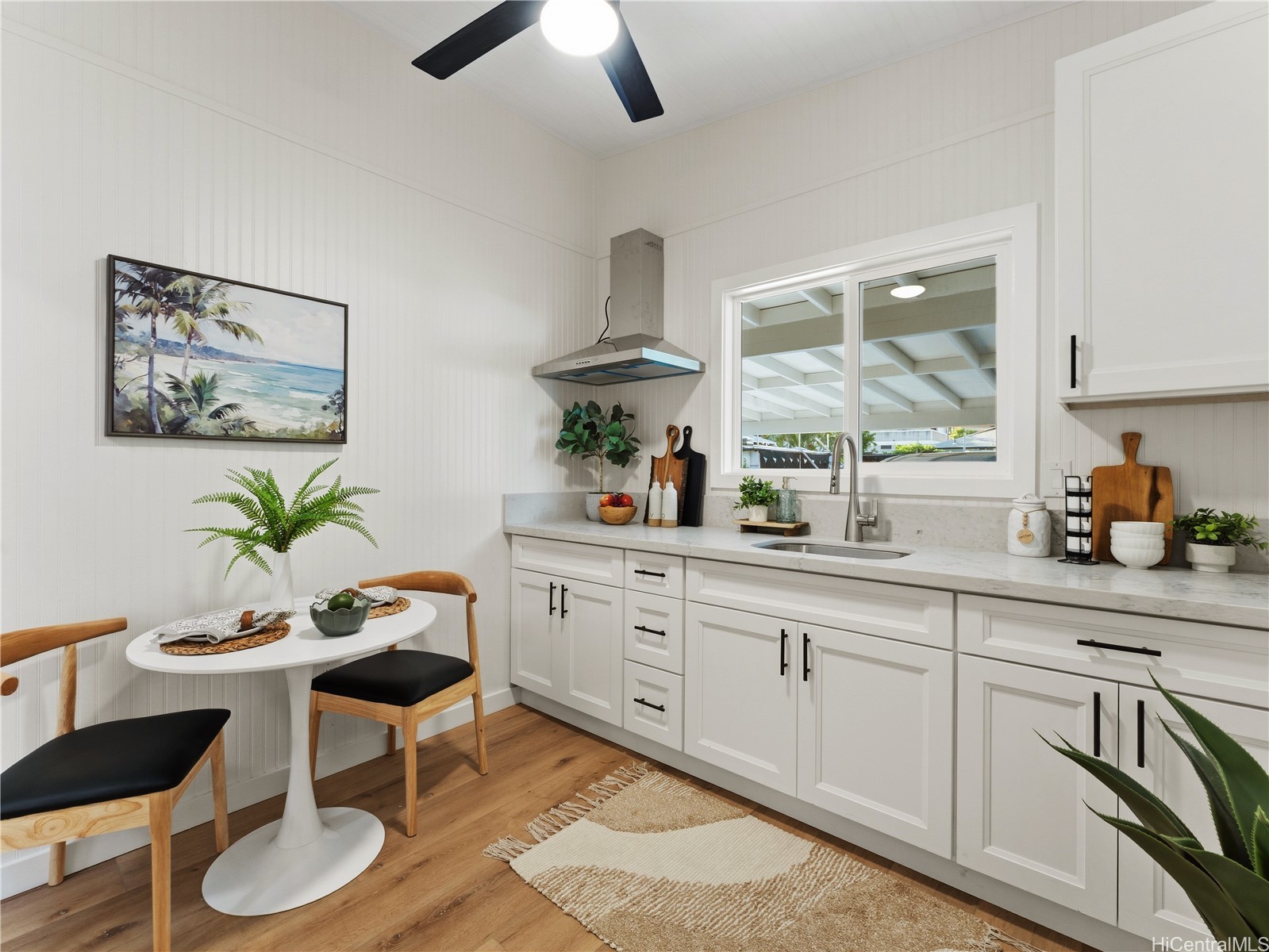 Staged kitchen with white cabinets, a window over the sink, and a small dining nook.
