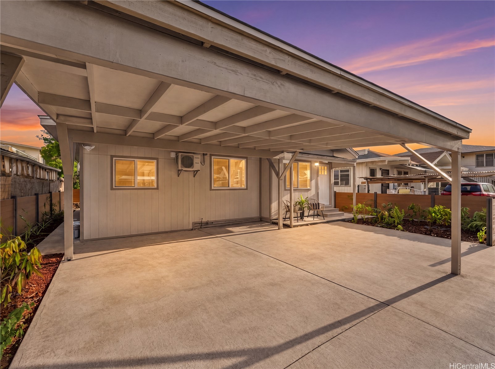 Home exterior with a large carport and concrete driveway at sunset.