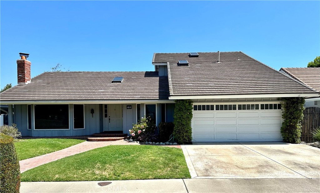 Blue single-story home with a tiled roof, front lawn, and attached two-car garage.