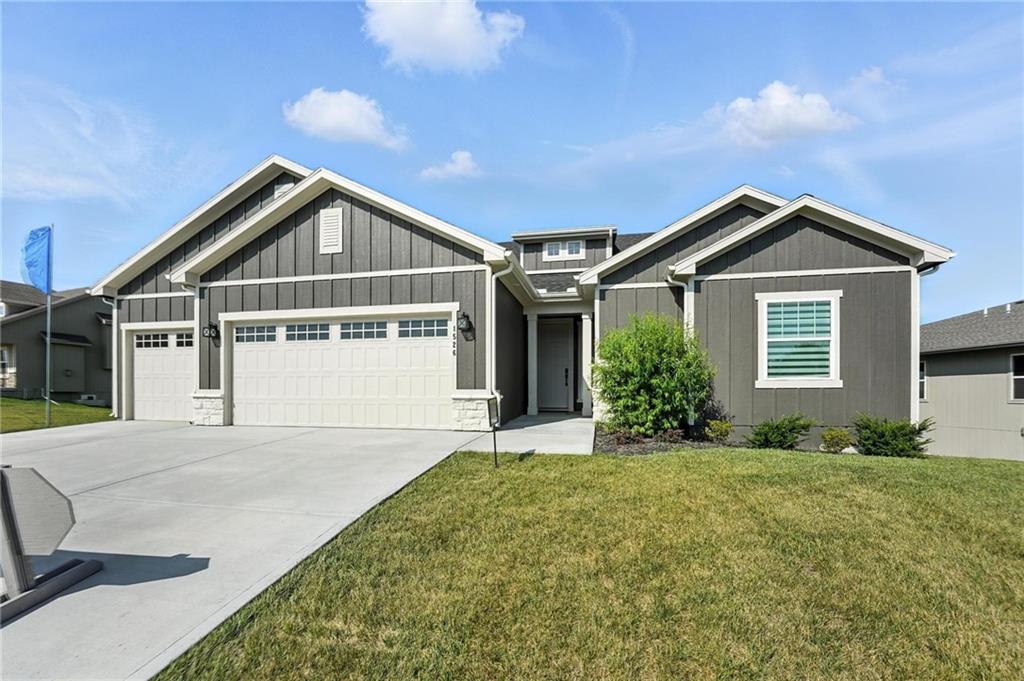 Gray single-story home with white trim, three-car garage, and broad concrete driveway.