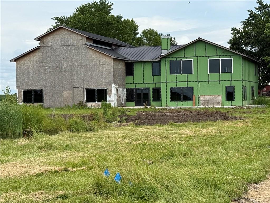 Two-story home under construction with green sheathing and a dark metal roof.