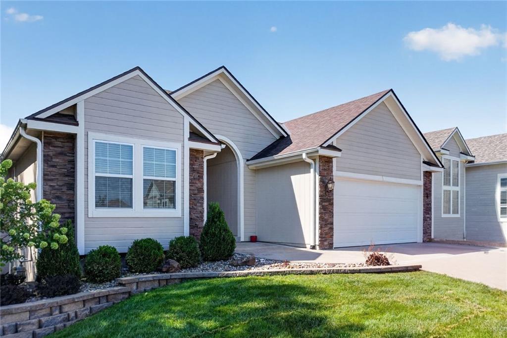 Gray single-story house with stone accents, two-car garage, and landscaped front lawn.