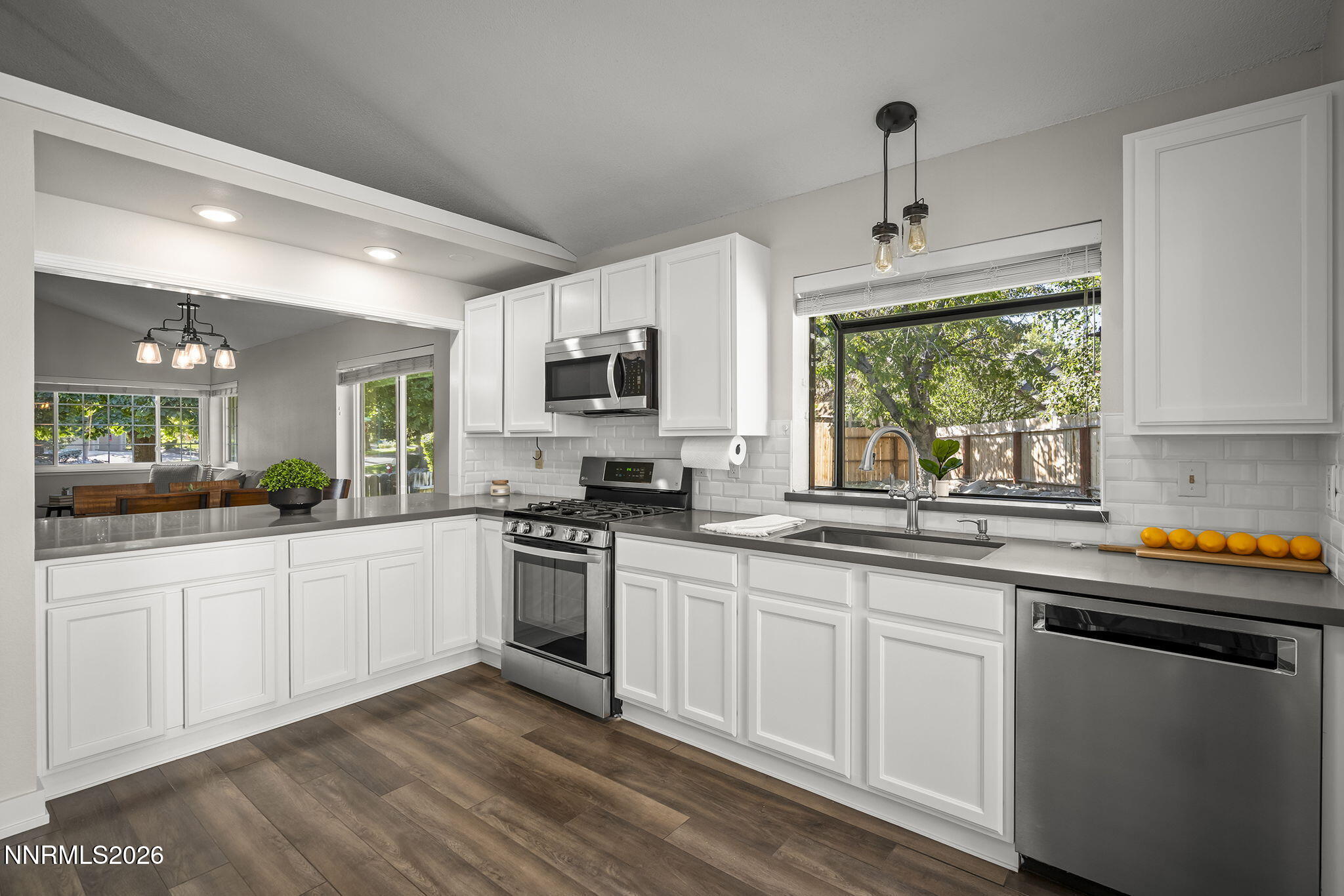 Bright kitchen with white cabinets, stainless appliances, and a large window above the sink.