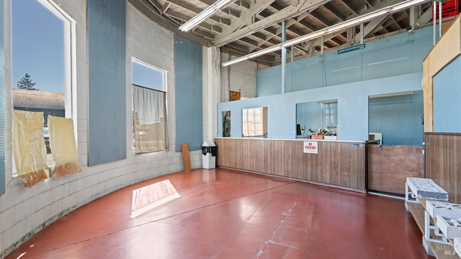 Commercial workshop interior with a red floor, exposed beams, blue wall panels, and a long service counter.