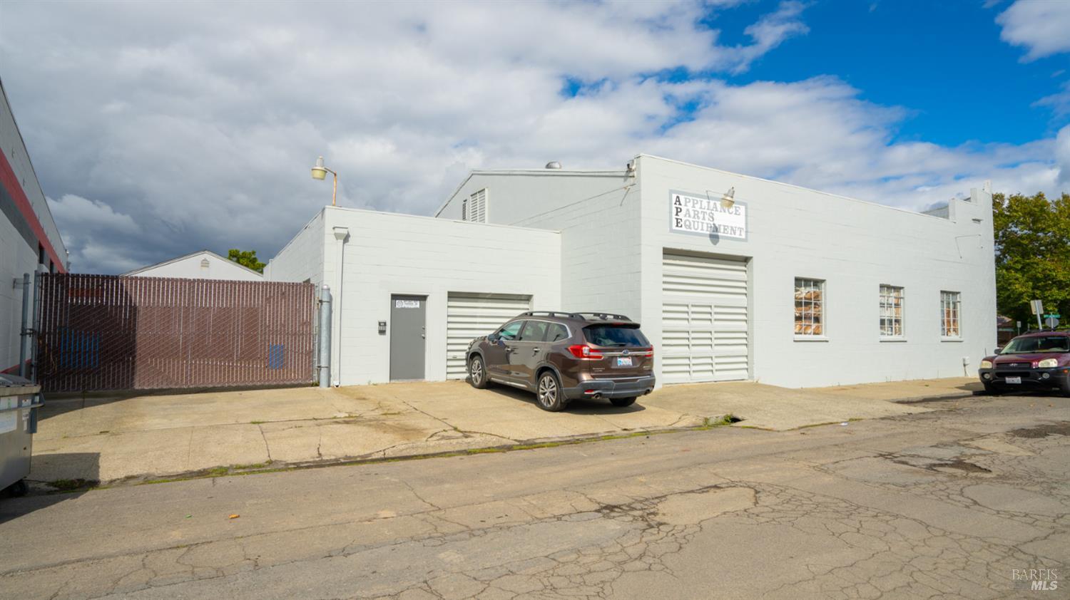 White commercial building with appliance parts sign and garage doors, viewed from the street.