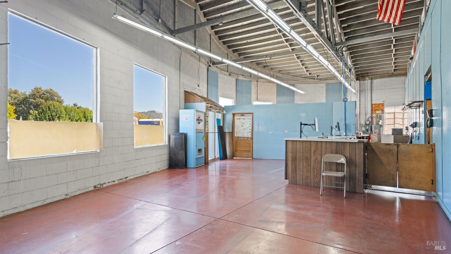 Industrial commercial interior with exposed beams, blue partitions, a red floor, and a service bay.