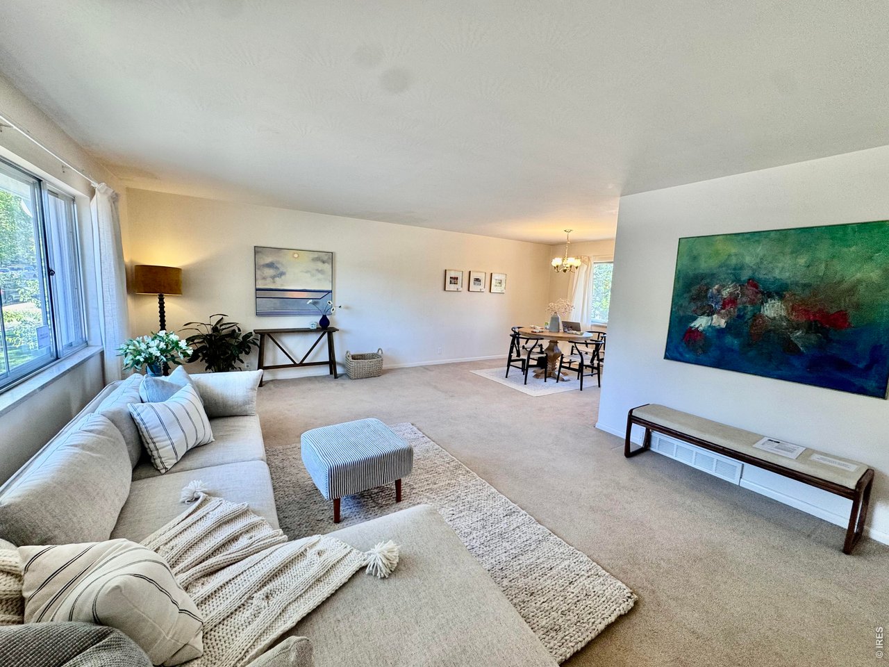 Living room with a light sectional, large windows, and dining area beyond.