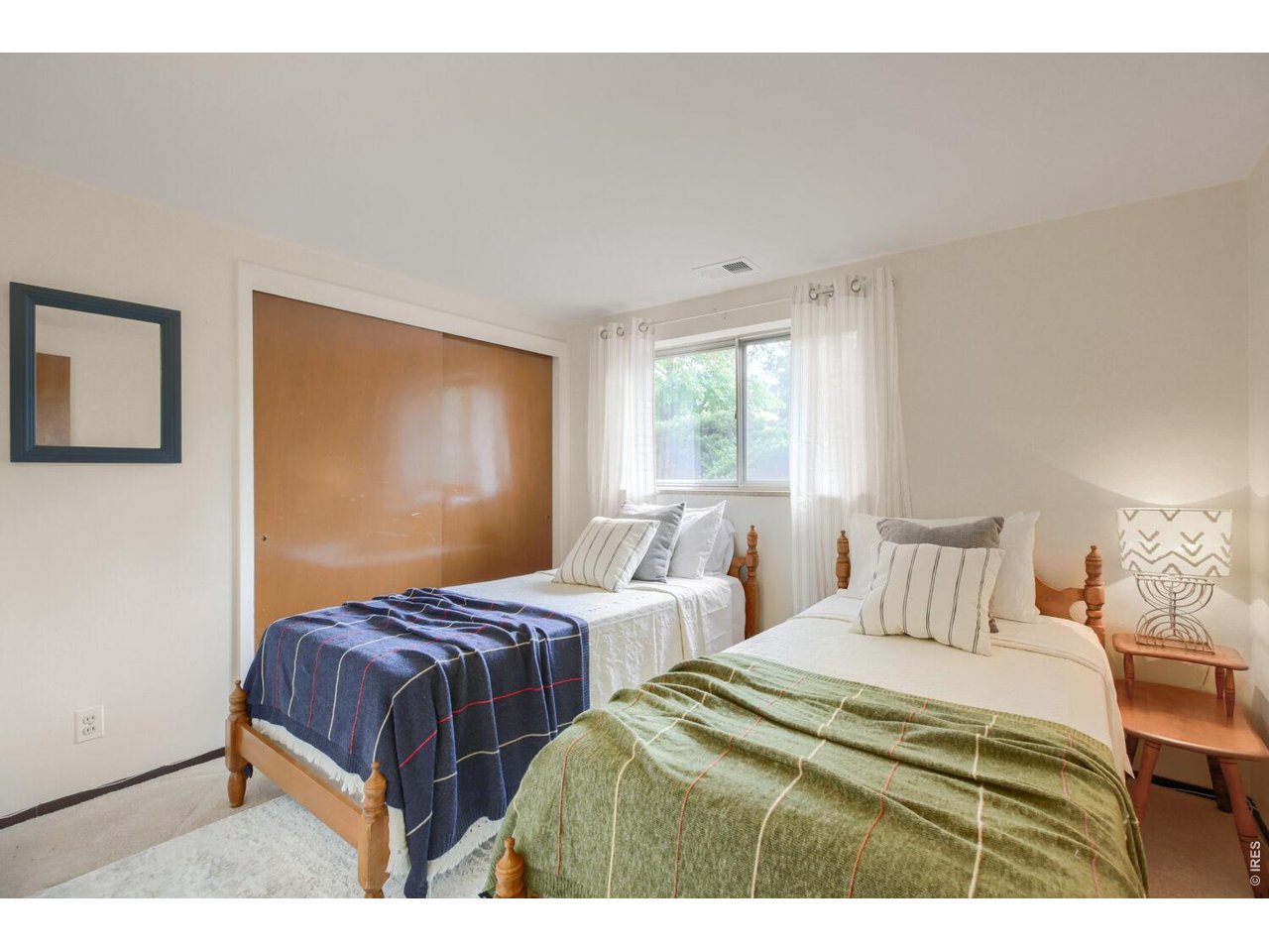 Bedroom with two wooden twin beds, patterned blankets, and a large sliding wooden closet door.