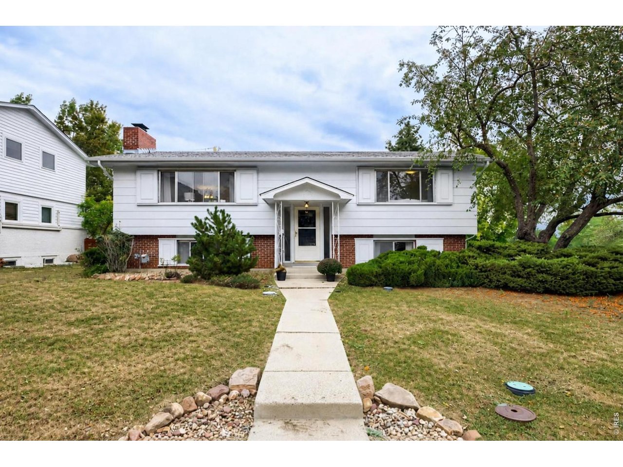 White split-level home with a brick lower facade and a walkway leading to the front entrance.