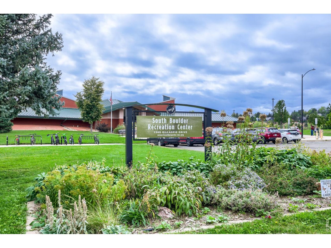 South Boulder Recreation Center behind a flower garden, with its sign in the foreground.