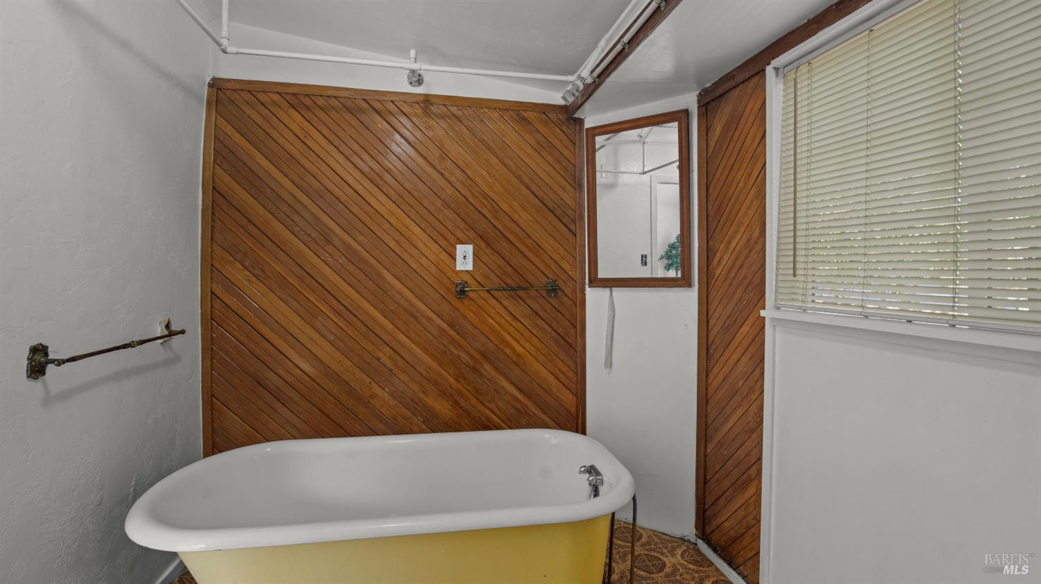Bathroom with a vintage yellow-and-white bathtub and diagonal wood-paneled walls.