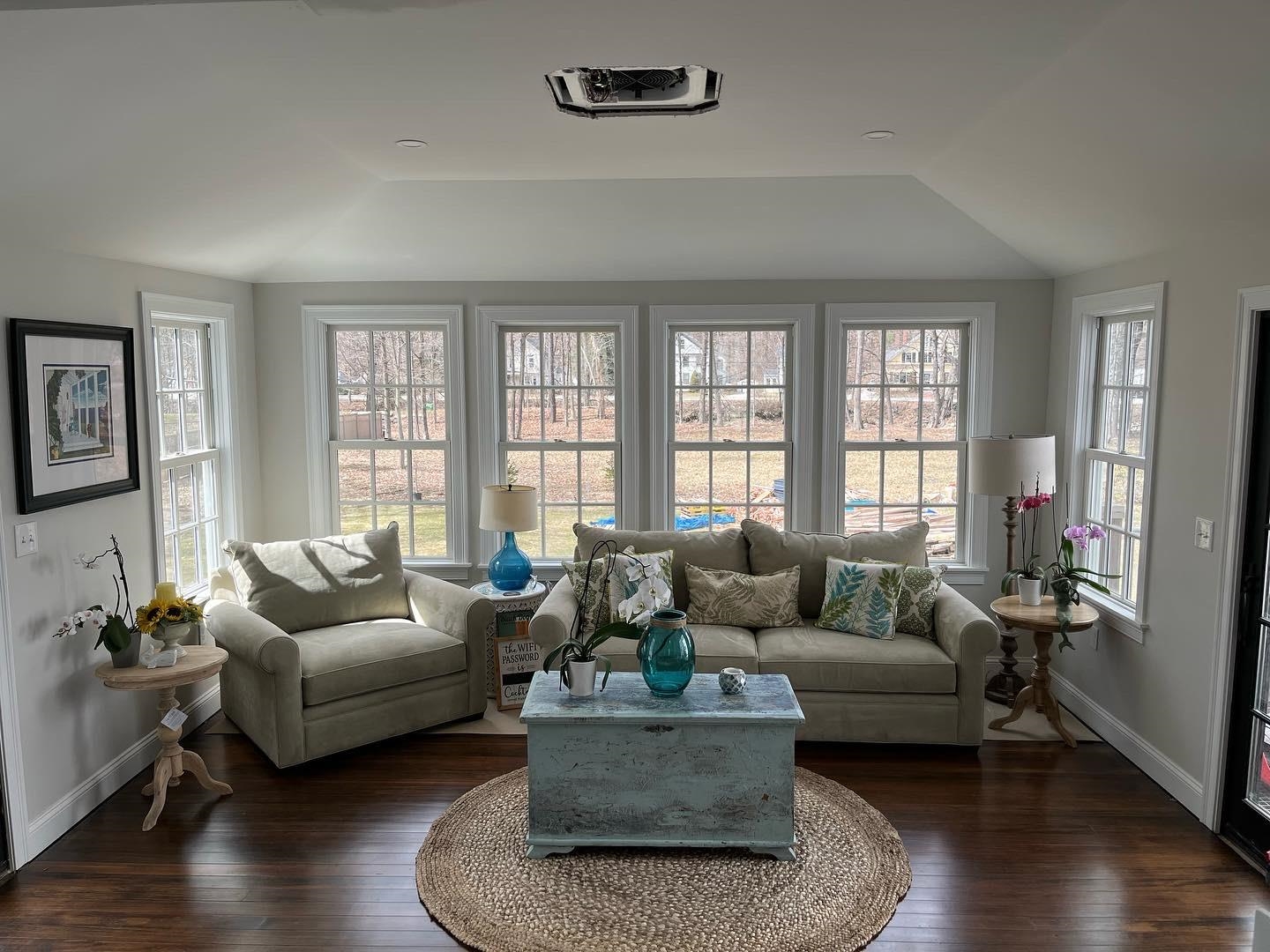 Living room with a light sofa, turquoise coffee table, and a wall of large windows.