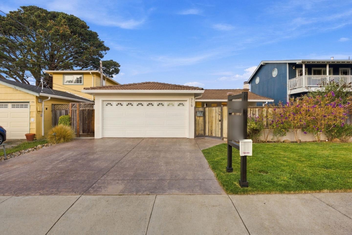 Single-story home with a white garage door, broad driveway, and black mailbox beside the lawn.