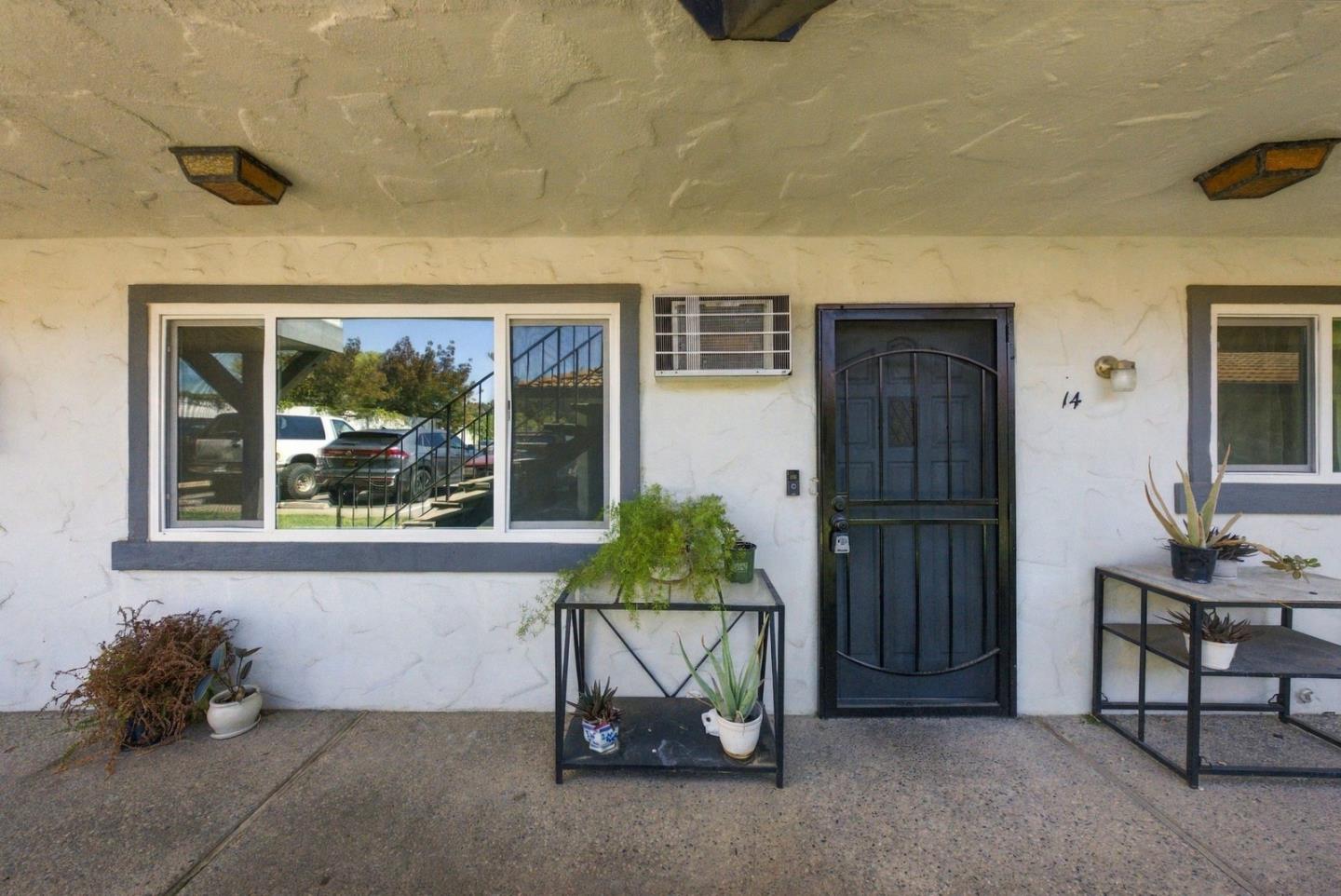 Residential entrance with a black door marked 14, a large window, and potted plants.