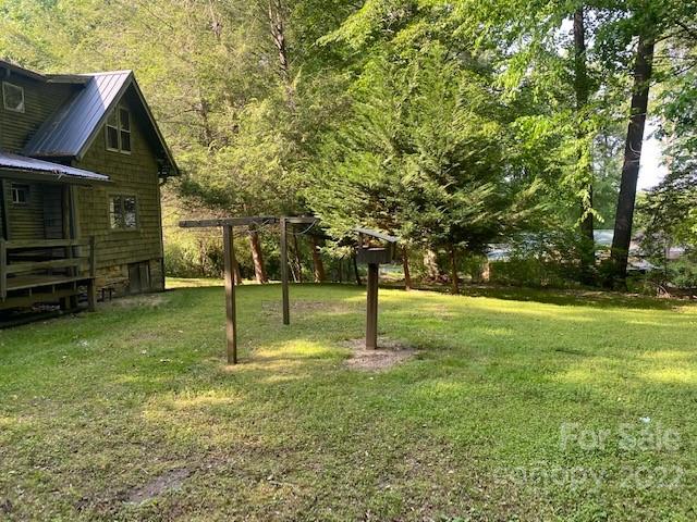 Cabin beside a grassy, tree-lined yard with a wooden clothesline frame.