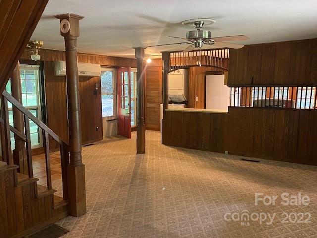 Open kitchen with a dark wood peninsula, tiled floor, arched divider, and staircase.