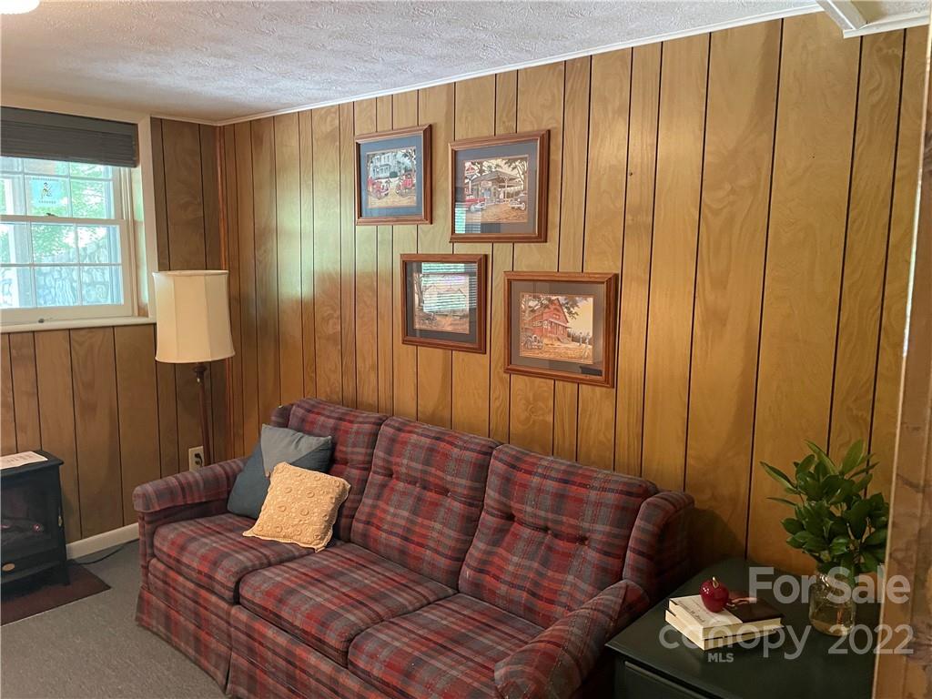 Living room with wood-paneled walls, a red plaid sofa, and framed artwork.