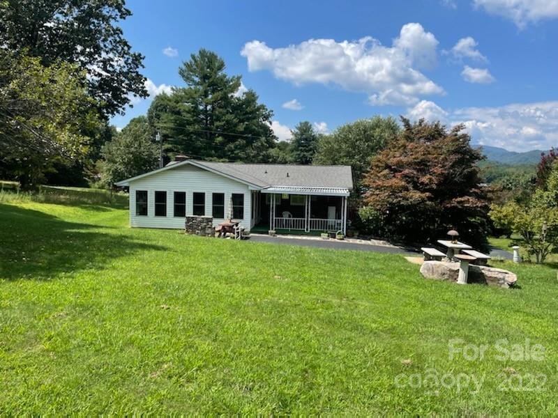 Single-story white house with a covered porch, broad lawn, and distant mountain view.