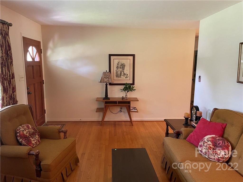 Living room with hardwood floors, paired armchairs, and a console table beneath framed artwork.