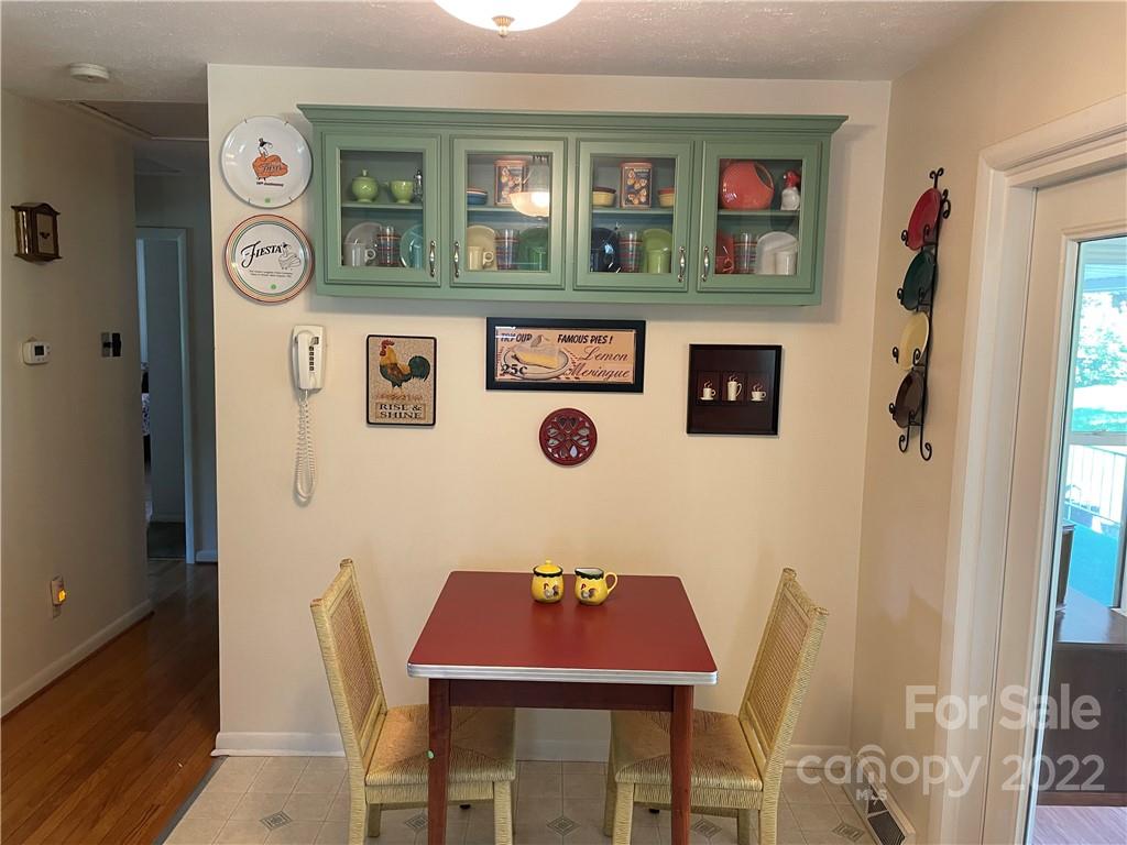 Dining nook with a red table, woven chairs, and a green glass-front cabinet displaying dishes.