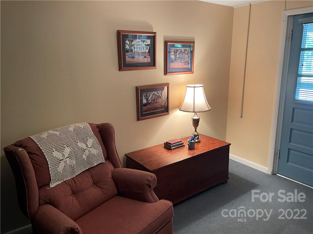 Furnished sitting area with a burgundy recliner, wooden desk, lit lamp, and blue door.