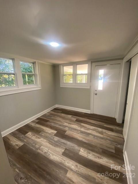 Unfurnished room with gray walls, multiple windows, and brown wood-look plank flooring.