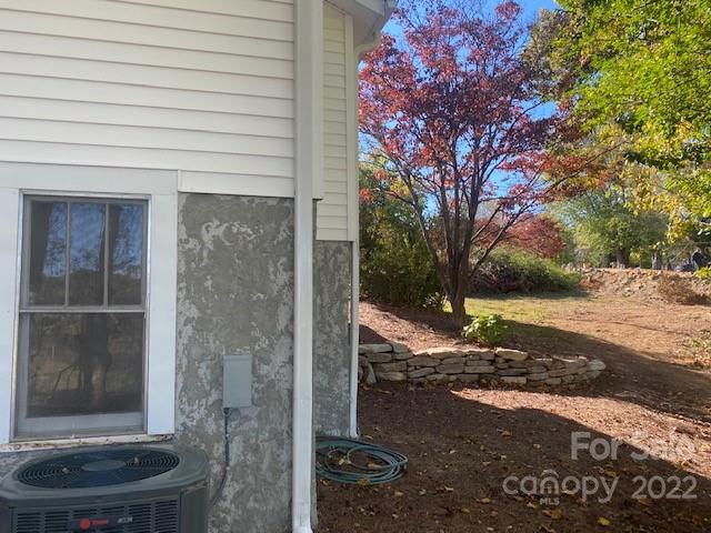 House side exterior beside a sloped yard with a stone retaining wall and colorful autumn trees.