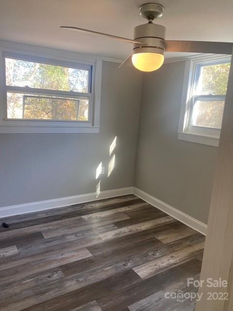 Vacant room with two windows, wood-look flooring, and a ceiling fan with a light.