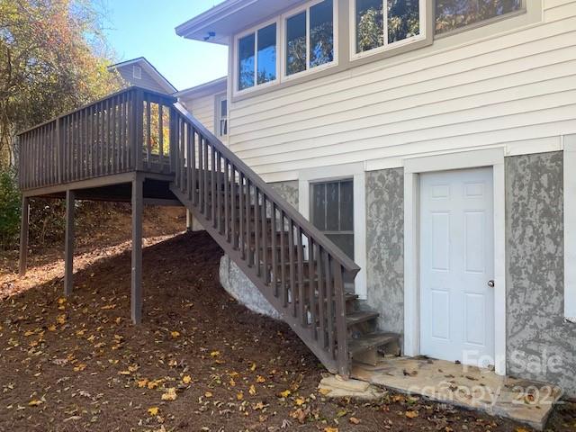 Raised wooden deck and staircase beside a home's lower-level entry.