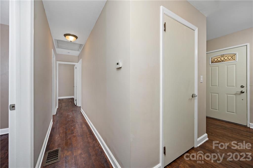 Interior hallway with dark wood floors and a paneled front door with decorative glass.