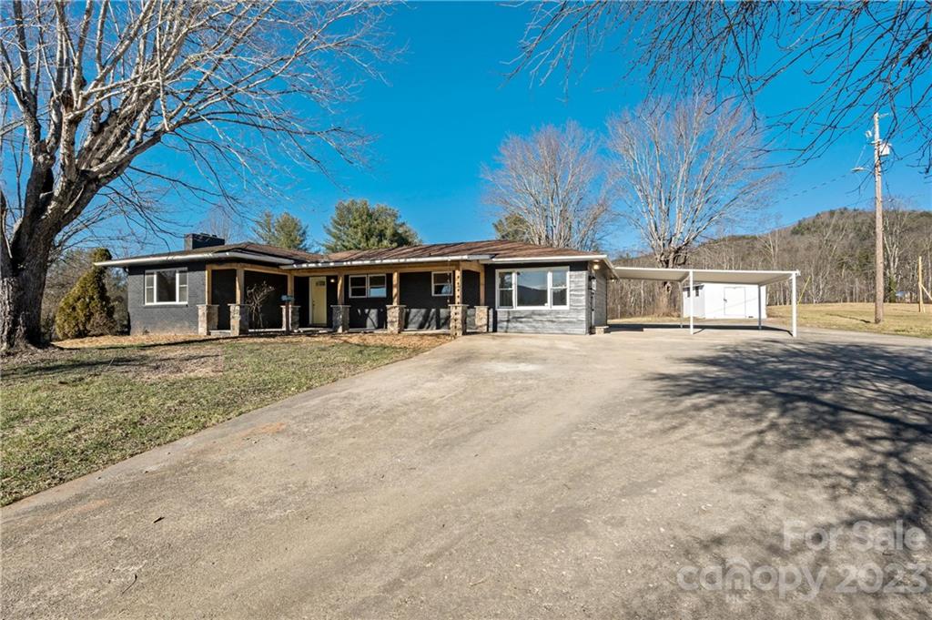 Single-story house with a broad concrete driveway and white covered carport.