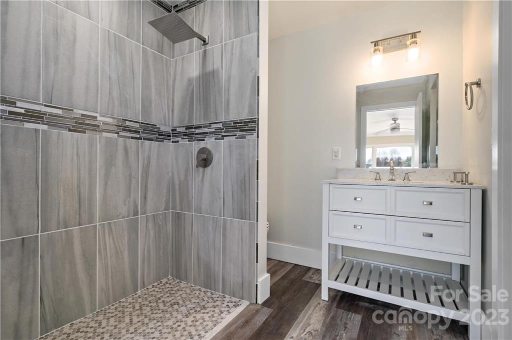 Bathroom with a gray-tiled walk-in shower and white double-sink vanity.
