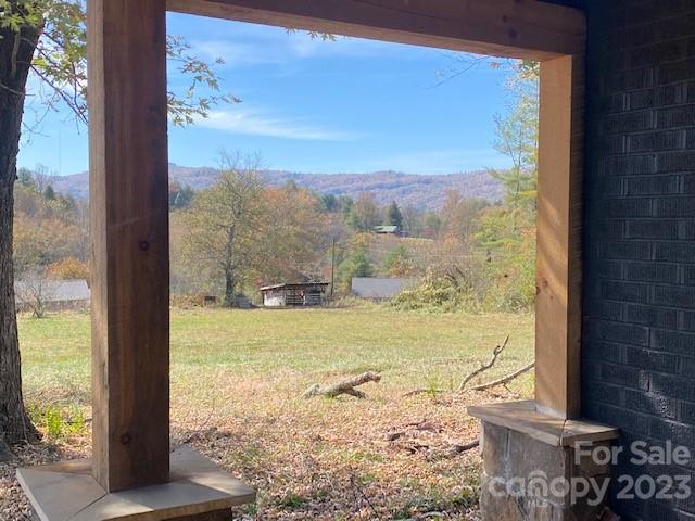Rural field and autumn mountain view framed by a covered porch.