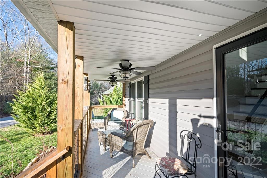 Covered porch with wicker seating, ceiling fans, and a view of the yard.