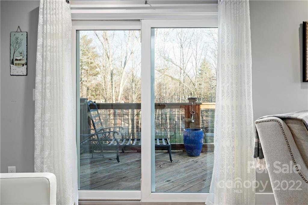 Living room sliding doors open onto a wood deck with chairs and a blue planter.