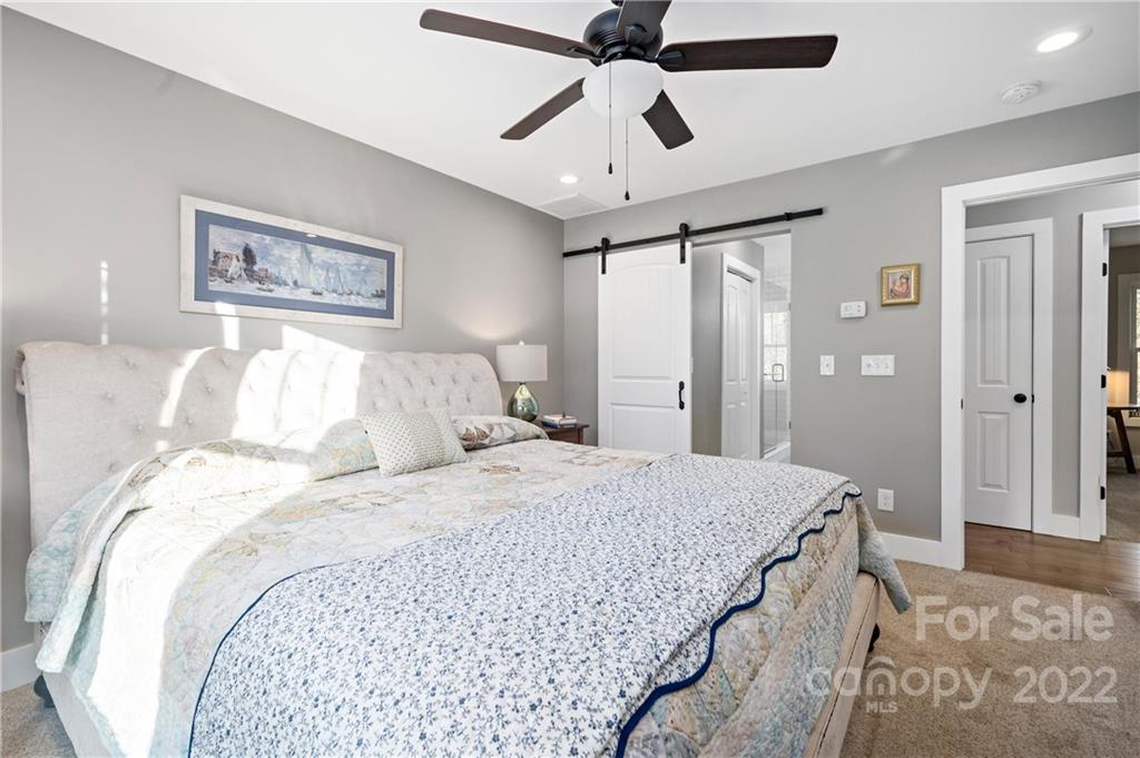 Furnished bedroom with a floral quilted bed and white sliding barn door.