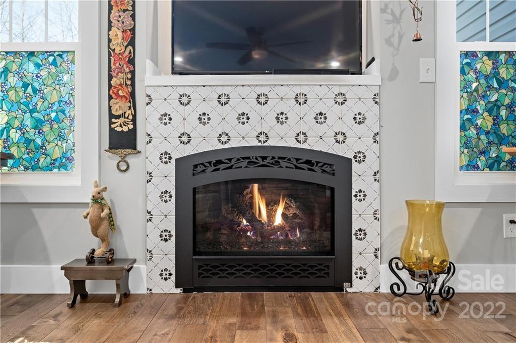 Living room fireplace with patterned tile surround, burning fire, and colorful stained-glass windows.