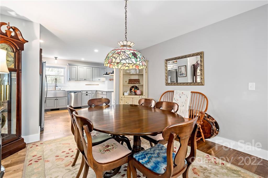Dining room with an oval wooden table, stained-glass pendant, and open view into the kitchen.