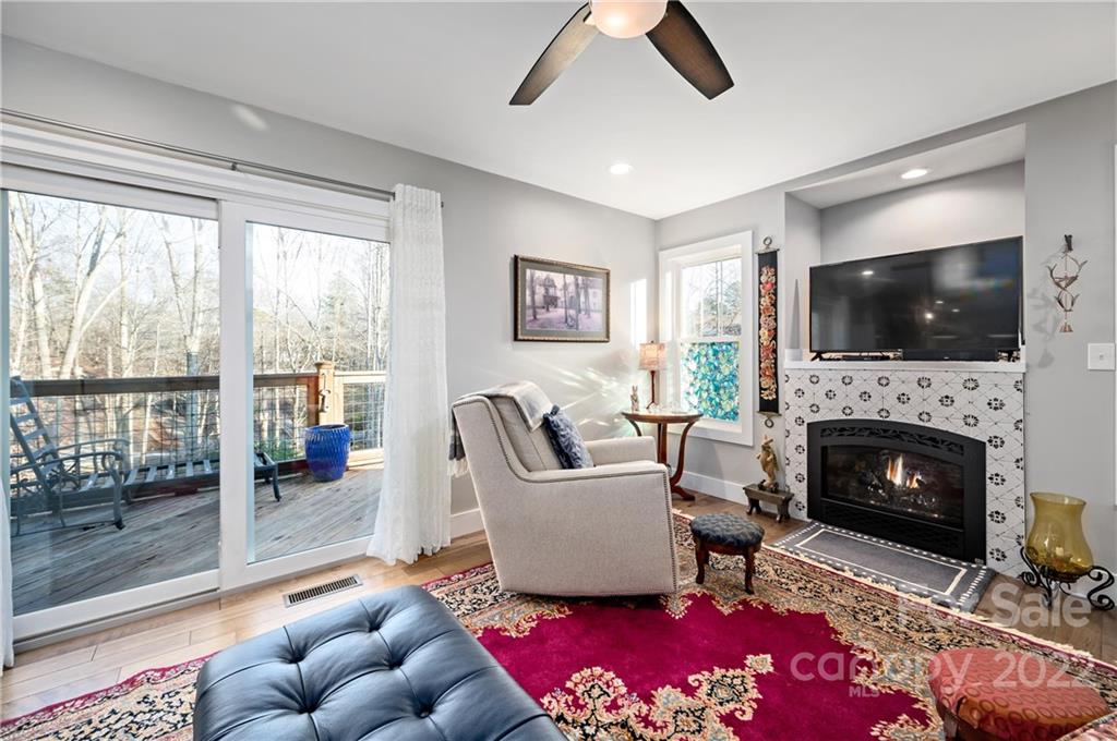 Furnished living room with a patterned fireplace, television, and sliding doors to a deck.