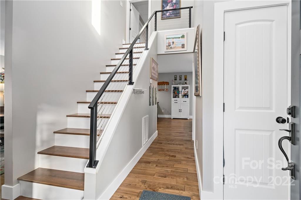 Home entryway with wood floors and a staircase featuring black cable railing.