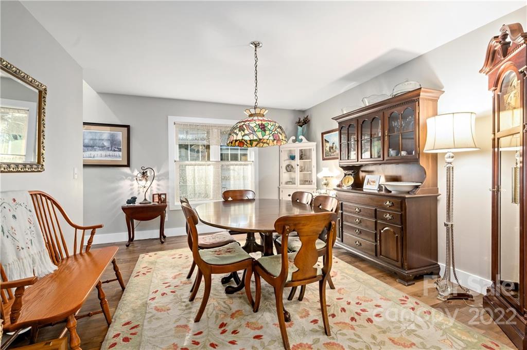 Dining room with a dark wood table, china cabinet, grandfather clock, and stained-glass pendant light.