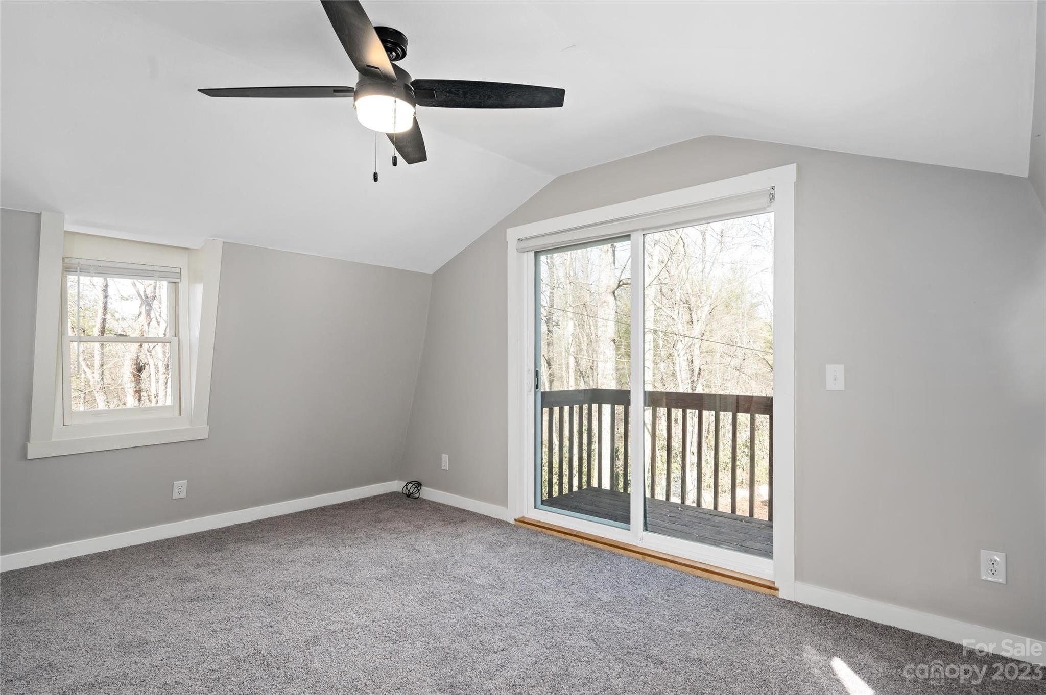 Empty carpeted bedroom with a ceiling fan and sliding glass door to a balcony.