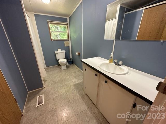 Bathroom with blue-gray walls, a window above the toilet, and a long white vanity.