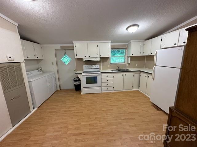 Unfurnished kitchen with white cabinets, white appliances, laminate flooring, and a washer and dryer.