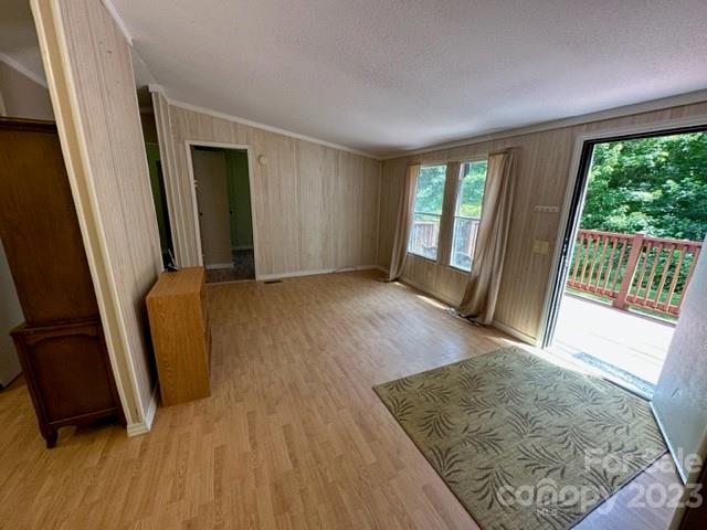 Living room with light wood flooring and an open sliding door to a deck.